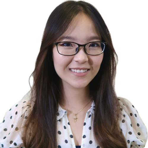 Smiling woman with long dark hair and glasses, wearing a white polka-dot blouse.